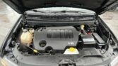 Open car hood revealing engine bay with V6 badge and visible fluid reservoirs and radiator area.