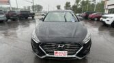 Front view of a black Hyundai in a rainy dealership lot, promotional plate reading 'E-Z YES You Can! Drive Away Today!'.