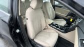 Interior of a car with beige cloth front seats and center console, viewed from the driver’s side with the door open.