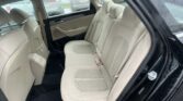 Back seat area of a beige leather car interior with headrests, rain-streaked windows visible outside.