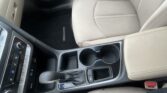 Beige leather car interior focusing on center console with gear shifter and cup holders.