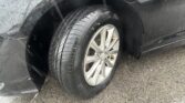 Close-up of a dark SUV wheel and tire, wet from rain, with raindrops on the body.