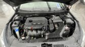 Open car hood revealing the engine bay with wet surfaces and windshield wipers visible in rain.