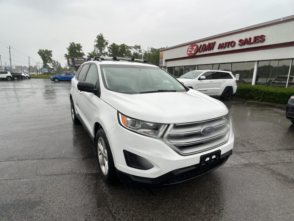 White Ford SUV in a car lot outside EZ Loan Auto Sales on a rainy day, with other vehicles and a glass-front showroom nearby.