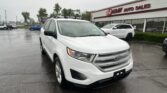 White Ford SUV in a car lot outside EZ Loan Auto Sales on a rainy day, with other vehicles and a glass-front showroom nearby.