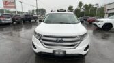 Front view of a white Ford SUV in a rainy car dealership lot with an E-Z Loan Auto Sales sign in the background.
