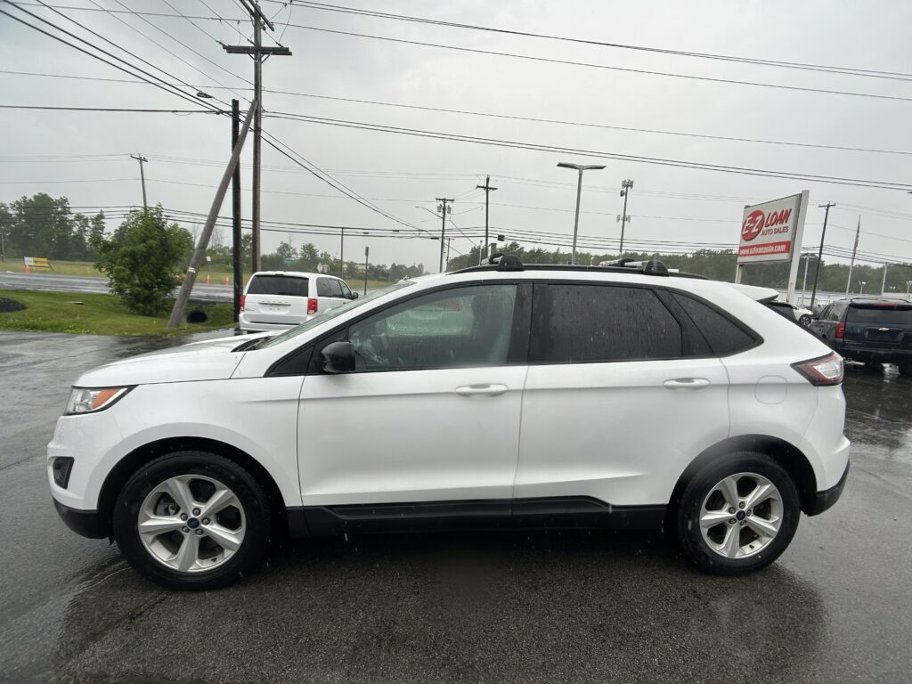 White SUV parked in a rainy car lot with power lines overhead and an EZ Loan Auto Sales sign in the background.