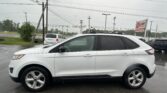 White SUV parked in a rainy car lot with power lines overhead and an EZ Loan Auto Sales sign in the background.