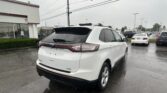 White SUV with roof rack in a rainy dealership parking lot, other cars in the background.