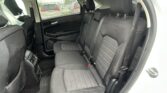 Back seat of a black car with three seats, headrests, and rear door panel visible; rainy window outside.