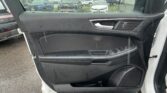 Interior view of a car door with a rain-spattered window showing a parking lot outside, through the side window.