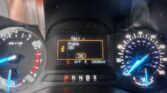 Car dashboard view showing left tachometer and right speedometer, with a central orange display reading “Trip 1 Engine ON,” gear selector PRND S below, odometer 124,308 mi, and ambient temperature about 60°F; illuminated warning icons visible.