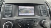 Rear-view camera feed on car display with parking guideline lines in green, yellow, and red.