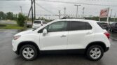 White SUV in a wet parking lot with other vehicles and a large EZ Loan Auto Sales sign in the background under cloudy skies.