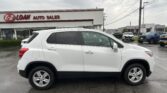 White SUV in the foreground at an EZ LOAN Auto Sales dealership with the sign on the building visible behind it, and other cars in the lot to the right.