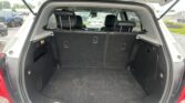 Open SUV trunk showing empty cargo area with rear seats upright and folded headrests visible in a parking lot.