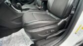 Driver’s side interior of a car with black leather seats, center console, gear lever, and a protective paper floor mat.