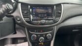 Car interior focusing on the center touchscreen displaying radio info (FM 106.5) surrounded by climate controls and dashboard details