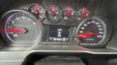 Close-up of a car dashboard showing circular gauges with red needles and a central screen displaying Speed 0 MPH (P R N D L gear indicator).