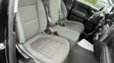 Interior of a pickup truck cabin with gray fabric seats, driver and front passenger seats visible, rain on the windows and door open to the outside.