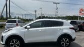 White SUV parked in a lot with other cars, power lines overhead and a roadside E-Z Auto sign in the distance