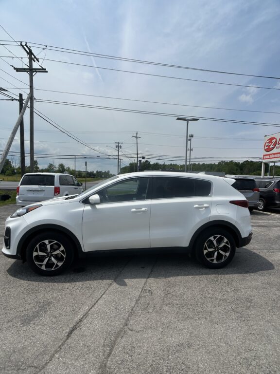 White SUV parked in a lot with other cars, power lines overhead and a roadside E-Z Auto sign in the distance