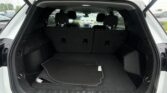 Open SUV trunk with folded rear seats and cargo mat visible in a rain-soaked parking lot.