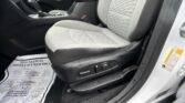 Car interior focusing on the front passenger seat, center console, and door sill with a patterned gray seat and a protective paper floor mat nearby.