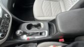 Front passenger seat in light gray quilted fabric, center console with cup holders visible nearby.