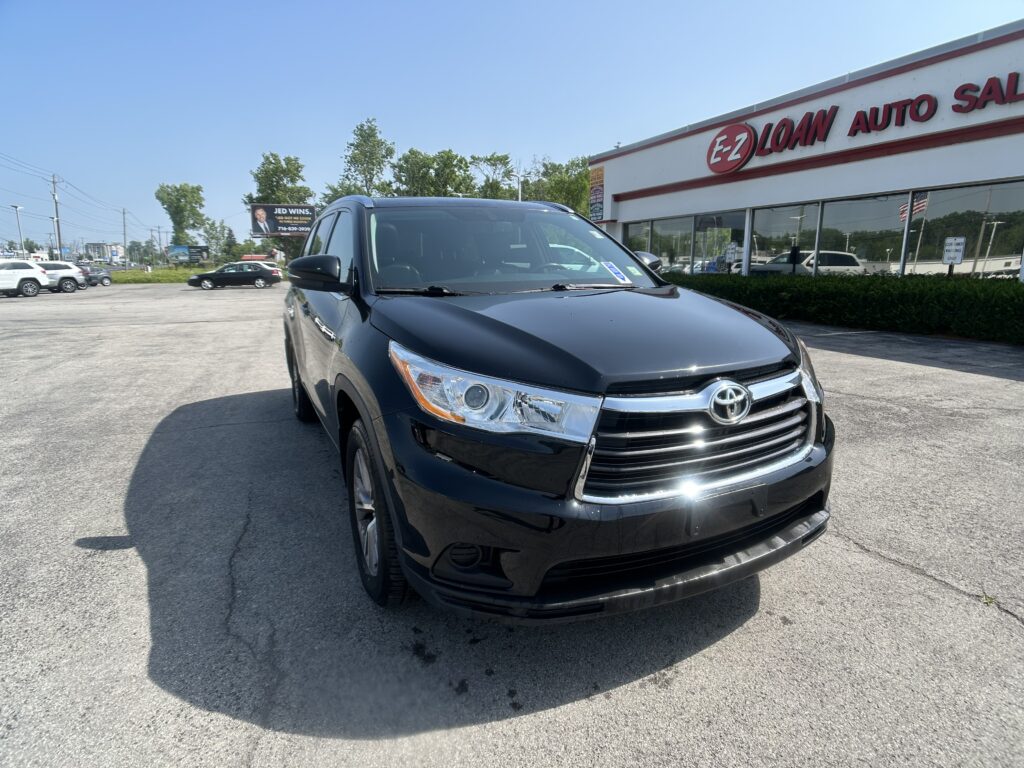 Black Toyota SUV in the dealership lot, with EZ Loan Auto Sales storefront in the background on a sunny day