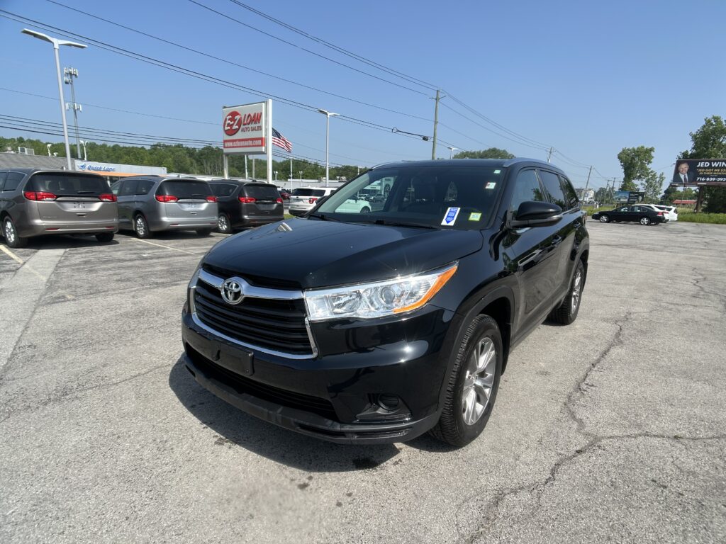 Front-right view of a black SUV in a dealership lot, with several minivans in the background and an EZ Loan Auto Sales sign nearby