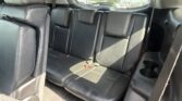 Black leather rear SUV seats with headrests and seat belts; street scene visible through the rear window.
