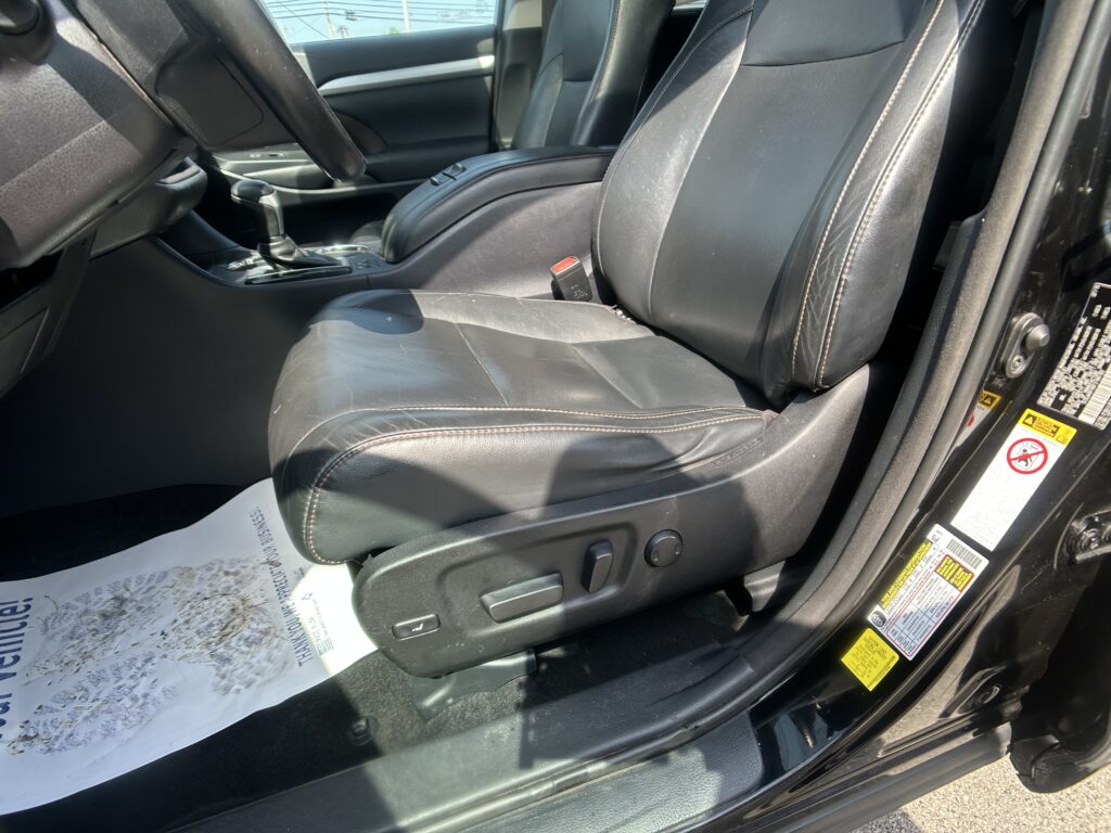 Inside front driver and passenger area of a car with black leather seats and center console, gear shifter, and door panel visible.