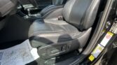 Inside front driver and passenger area of a car with black leather seats and center console, gear shifter, and door panel visible.