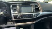 Dashboard interior of a car with center touchscreen and climate controls visible, passenger-side papers on the floor saying 'We Take Pride In Your Vehicle'