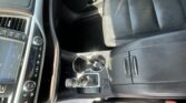 Interior of a car showing the center console with gear shifter, cup holder, and control buttons beside the driver's seat.