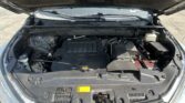 Under-hood view of a car engine bay with the hood raised, showing the V6 engine cover and battery on the right.
