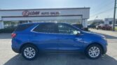 Blue Chevrolet Equinox SUV parked in front of the E-Z Loan Auto Sales storefront in a car dealership lot, with other vehicles visible in the background.