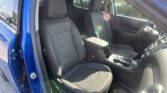 Blue car door open to reveal the front seat area with two black fabric seats and center console.