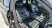 Black leather front seats inside an SUV, viewed with the driver’s door open and the center console visible
