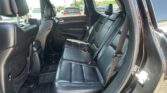 Back seat area of a black leather SUV with three seating positions and visible seat belts and headrests for passengers.