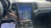 Interior of a car dashboard with a large vertical touchscreen display; a flyer on the passenger side reads 'We Take Pride In Your Vehicle'