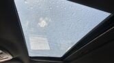 Sunroof viewed from inside a car, with raindrops scattered across the glass during daylight