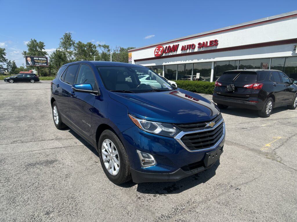 Blue SUV in the dealership lot with E-Z Loan Auto Sales storefront in the background on a sunny day.