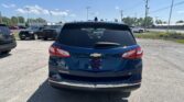 Rear view of a blue Chevrolet Equinox LT in a parking lot, with other cars and a clear blue sky overhead.