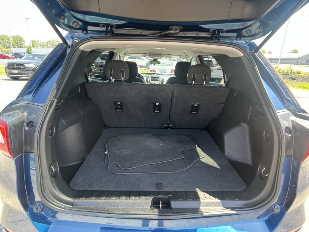 Open hatchback trunk of a blue SUV with rear seats upright and cargo floor visible
