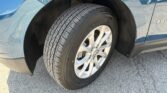 Close-up of a blue SUV front wheel and tire, showing wheel well and the Equinox badge on the side panel.