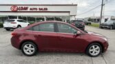 Maroon sedan in foreground outside E-Z Loan Auto Sales dealership with building and other cars in lot behind it
