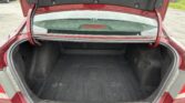 Open red car trunk showing a spacious black-carpeted cargo area and rear windshield visible from above.