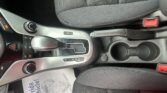 Center console of a car showing gear shifter, climate controls, and a paper on the floor by the seat.